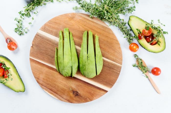 avokado skivor, placerade på runda trä skärbräda, avokado pommes frites recept, körsbärstomater runt dem