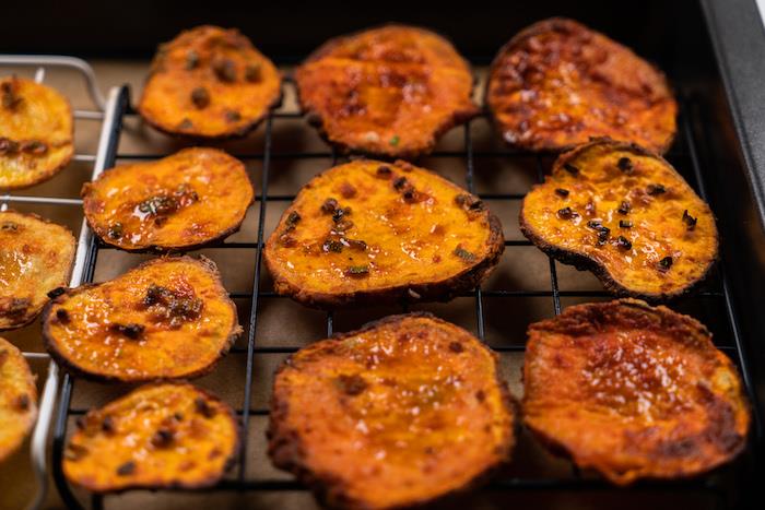 bakade potatischips, arrangerade på metallskena, hemlagat potatischipsrecept, i svartpappersklädd bakplåt