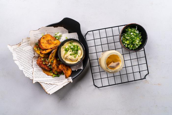 bakade chips placerade på papper i svart skål, recept på hemlagad potatischips, majonnässkål på sidan