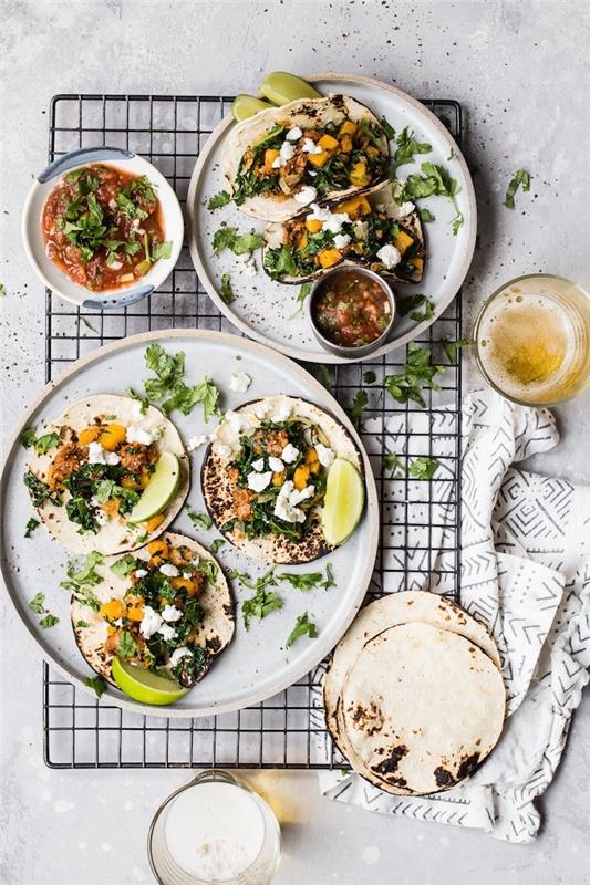 tortillavallar, fyllda med kött, hackade grönsaker, bästa tacokryddor, arrangerade på svart metallräcke