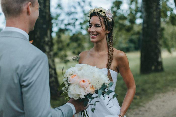 epi fläta på sidan med en krona av färska blommor, fria trådar, ärmlös vit bröllopsklänning