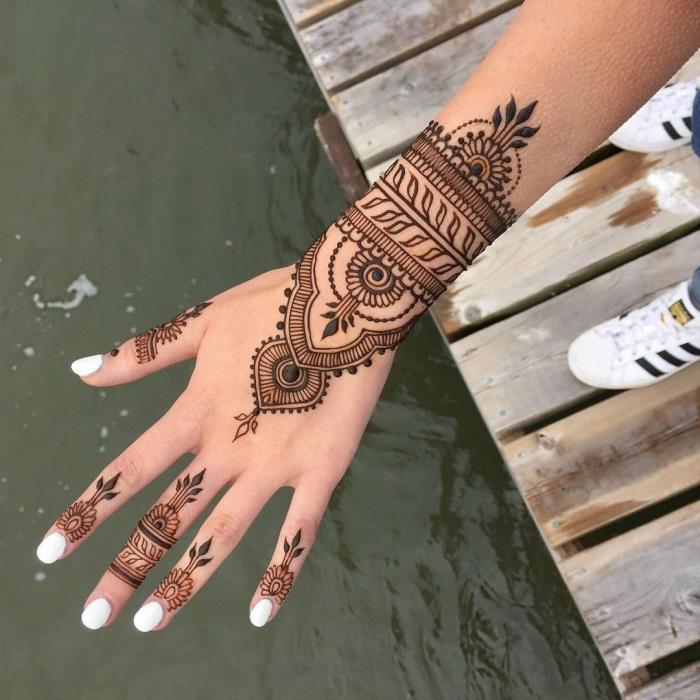 henna model ruky, manikúra s bielymi nechtami, čierne tetovanie hennou s etnickým dizajnom pre ženy