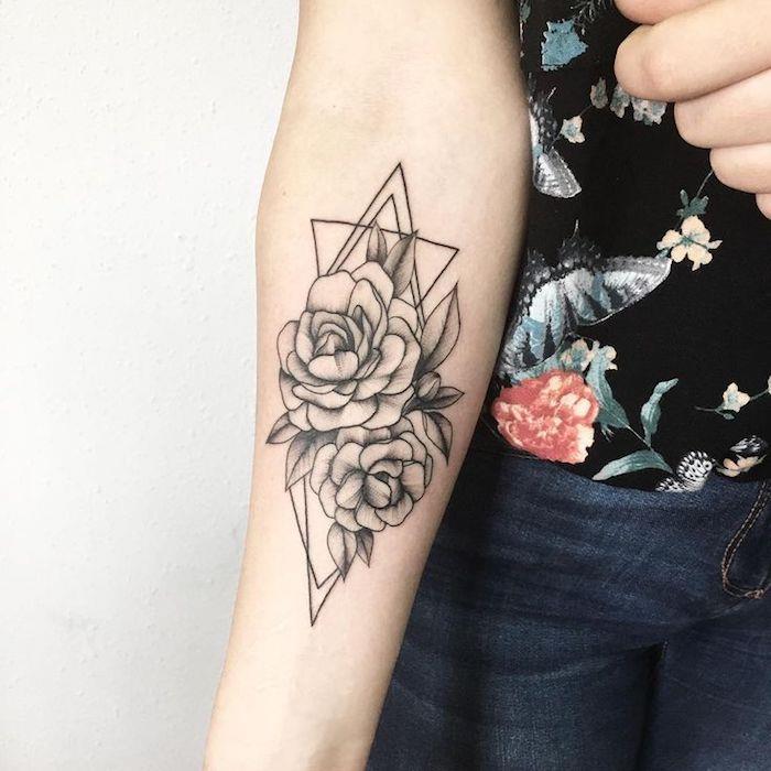 Il braccio di una donna tatuato con un fiore di loto e forme geometriche