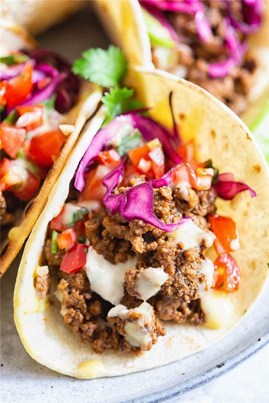 tortillainpackningar, fyllda med nötkött, hackad kål, salsasås, hur man gör tacokött, vit tallrik