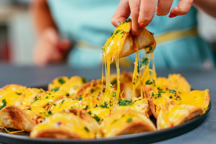 mini tacos, täckt med smält ost, mexikanska köttfärsrecept, arrangerade på en svart rund bricka