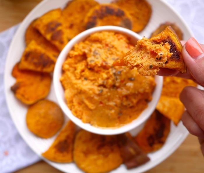 hummus i en vit skål, bakade sötpotatischips på sidan, enkla vegetariska aptitretare