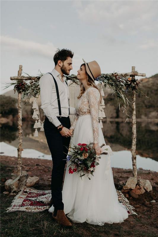 höga skor, svarta byxor, hängslen, vit skjorta, brud med filthatt och bukett röda blommor