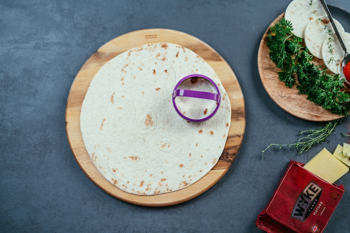 tortillapapper, skuren i mindre cirklar, på ett träbräda, på ett svart bord, tacorecept, paket ost