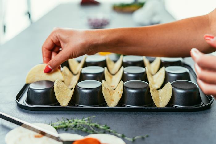 hur man gör tacos, tortilla -omslag, arrangerade på en svart muffinsbricka, kvinna med rött nagellack