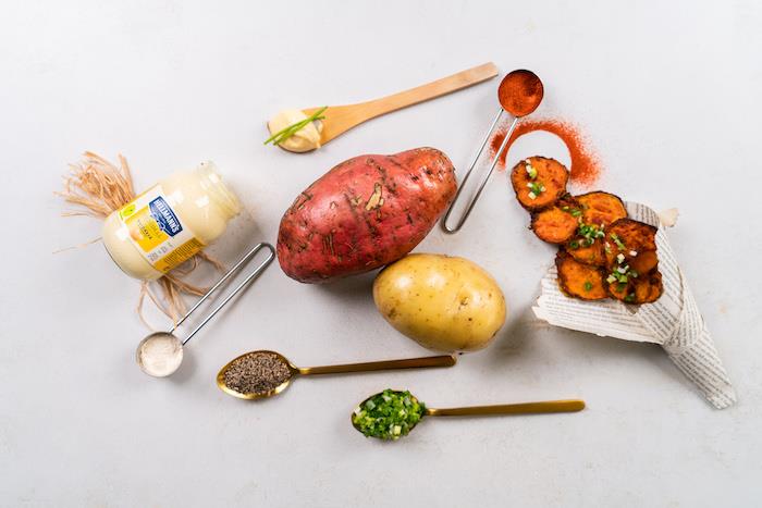 potatis och sötpotatis, olika ingredienser placerade på vit yta, bakade chips på papper på sidan, recept på hemlagad potatischips