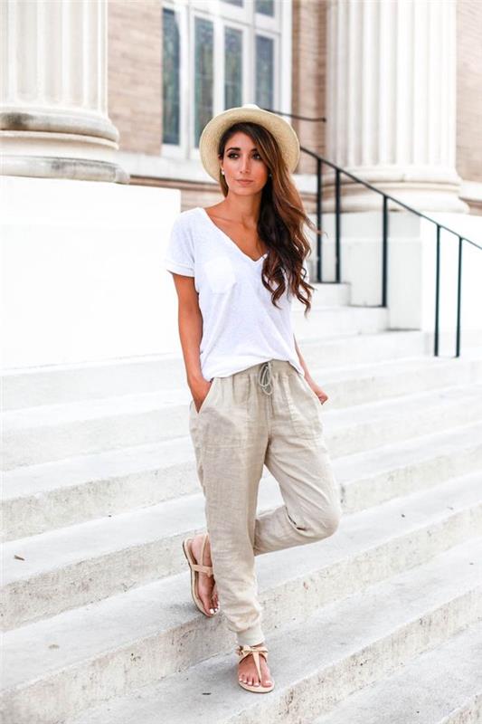 casual chic style woman, vit t-shirt och beige lösa byxor med beige sandaler, brunt lockigt hår