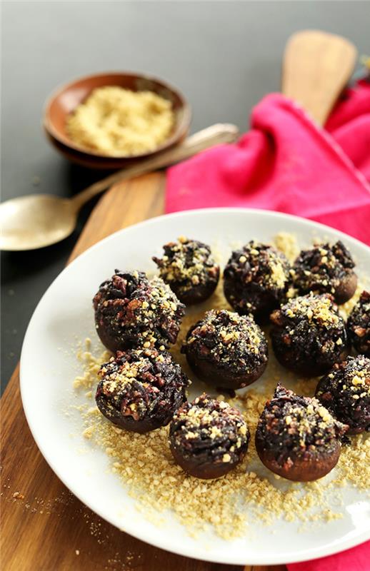 svampbett med nötter på toppen, vegetarisk fingermat, i en vit tallrik