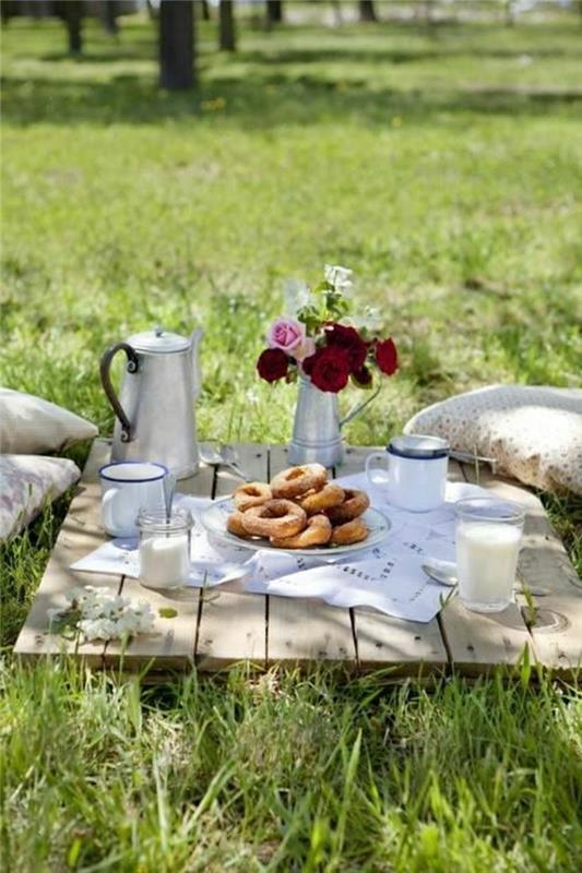 picknick-bord-grön-gräsmatta-blommor-på-trä-bordet-solig-trädgård