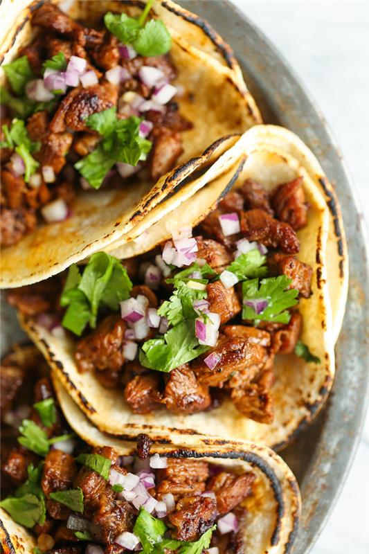 hård skal -taco, tortilla -omslag, fyllda med nötkött, lök och persilja, arrangerade på en silverfat