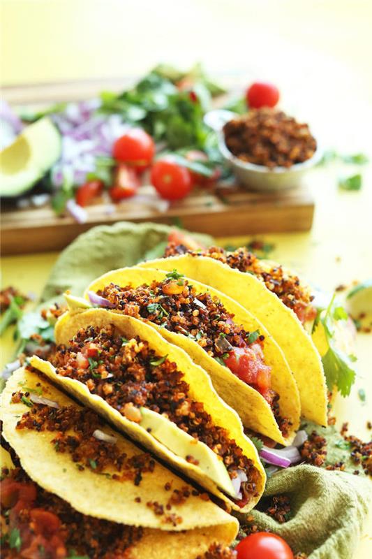 tortillainpackningar, fyllda med salsa, kokt quinoa, tacoingredienser, grön bordsduk, träskärbräda