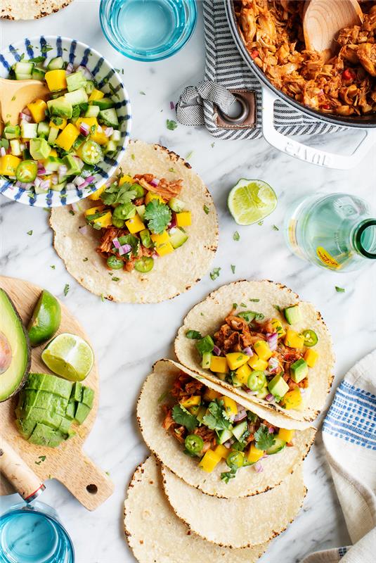 tortillainpackningar, fyllda med grönsaker, bästa tacokryddor, avokadoskivor, limeskivor, bänkskiva i marmor